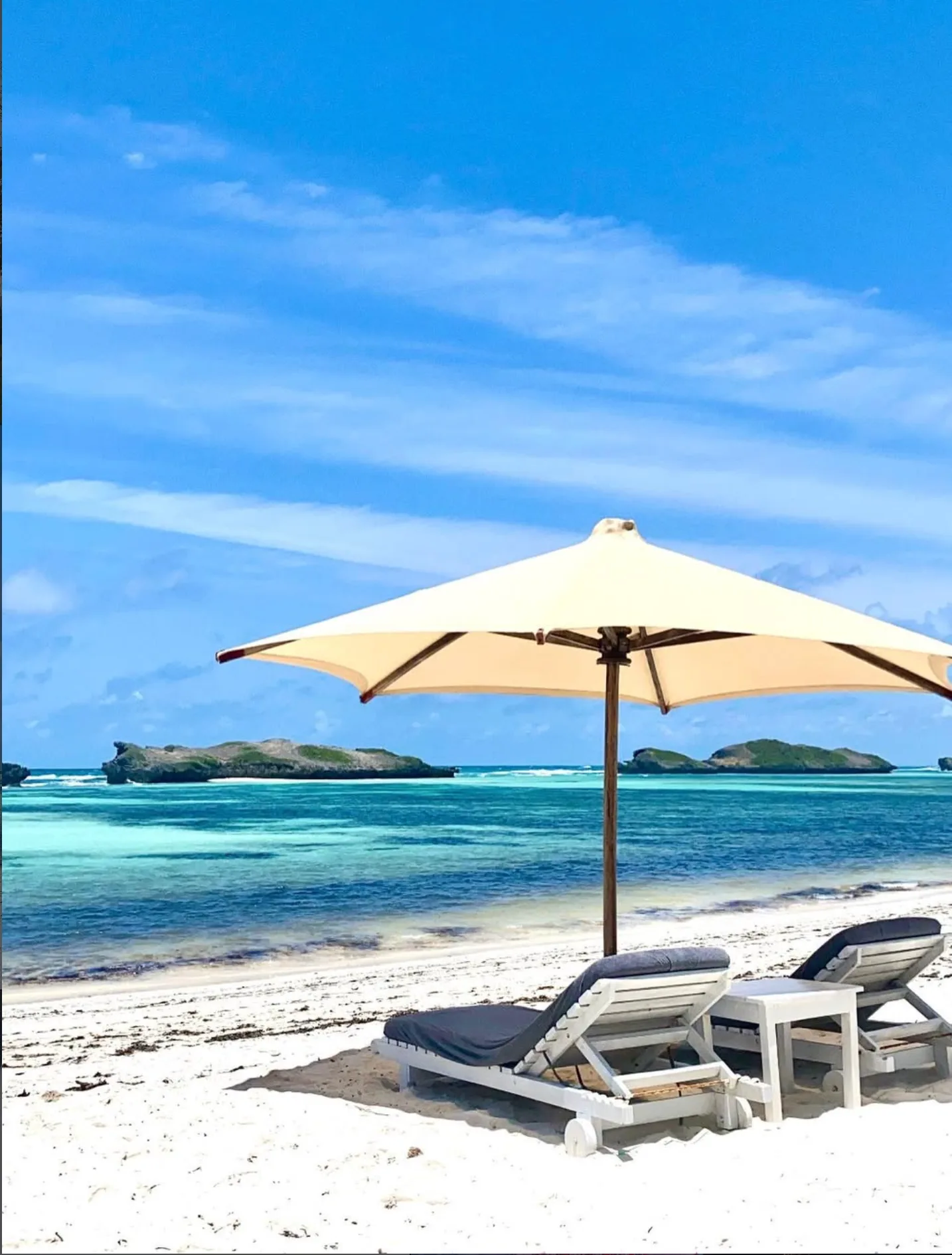 Tropical beach with white sand, turquoise ocean, and lounge chairs