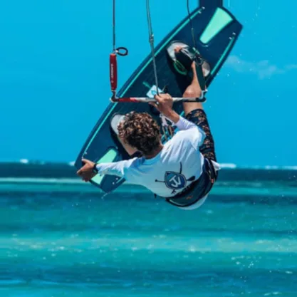Kitesurfing over turquoise ocean waters under clear blue sky